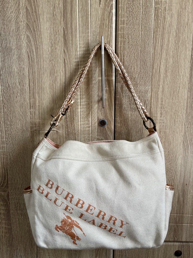 Burberry Blue Label Canvas Shoulder Bag (Category: Luxury Bags & Wallets) located in Calamba. Submitted by michCM (Listing ID 1441165274, Image 1). Description: - Authentic Burberry Blue Label white canvas shoulder bag - Elegant rose gold accents on straps and pocket edges - Iconic Burberry knight logo and 'Burberry Blue Label' print - Convenient side pockets for easy access - Stylish pink interior - Ideal for everyday wear and errands Issues: Co
