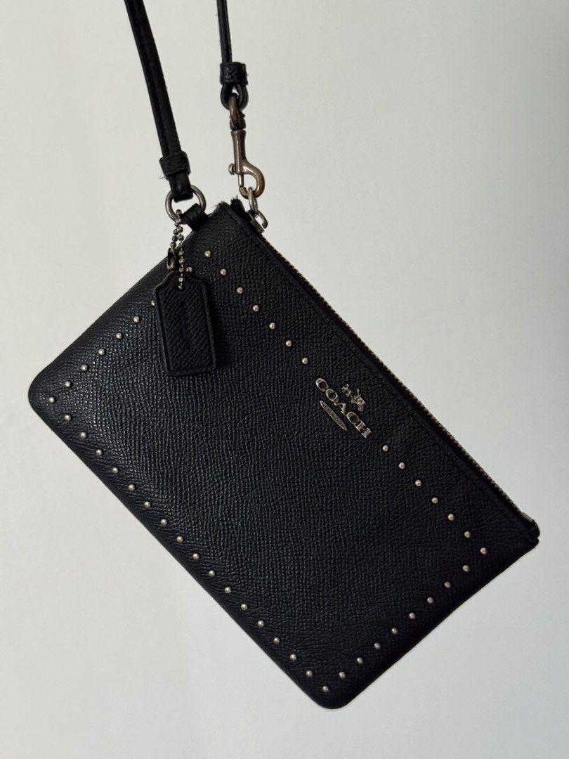 Coach Black Studded Leather Wristlet Pouch (Category: Luxury Bags & Wallets) located in Quezon City. Submitted by nbg.declutter (Listing ID 1441211437, Image 1). Description: - Authentic Coach black leather wristlet - Stylish studded detailing on the front - Secure zipper closure - Detachable wrist strap for versatility - Includes small Coach brand tag - Ideal for carrying your daily essentials.
