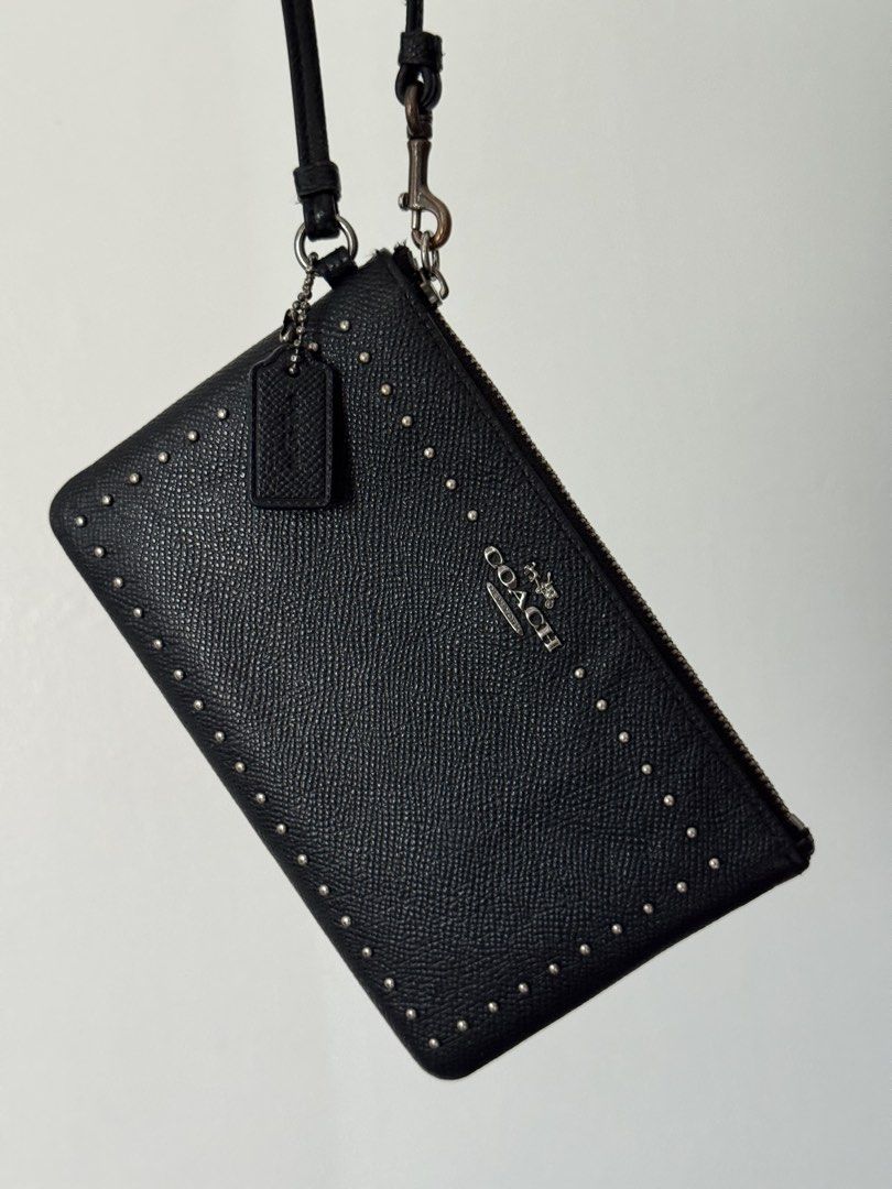 Coach Black Studded Leather Wristlet Pouch (Category: Luxury Bags & Wallets) located in Quezon City. Submitted by nbg.declutter (Listing ID 1441211437, Image 2). Description: - Authentic Coach black leather wristlet - Stylish studded detailing on the front - Secure zipper closure - Detachable wrist strap for versatility - Includes small Coach brand tag - Ideal for carrying your daily essentials.