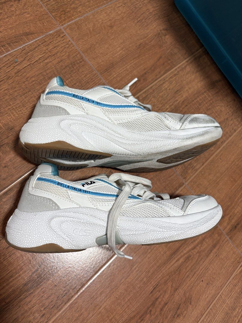 Fila White & Blue Badminton shoes (Category: Sneakers) located in Antipolo. Submitted by tagsale101 (Listing ID 1441306098, Image 2). Description: - White Fila sneakers - Blue accent details - Chunky sole design - Signs of wear on toe box and soles - Perfect for casual wear or light workouts.