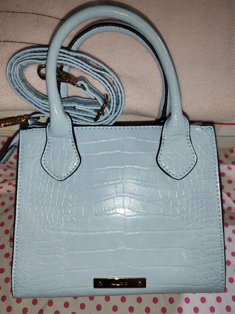 Light Blue Croc Embossed Top Handle Bag with Charms (Category: Cross-body Bags) located in Manila. Submitted by jazzlync (Listing ID 1441230831, Image 2). Description: Cute light blue handbag with croc embossed texture. Comes with a detachable crossbody strap. Adorned with fun charms like a smiley face, evil eye, and a teddy bear. Gold hardware details. Great for adding a pop of color to any outfit. Plenty of space inside for your essentials..