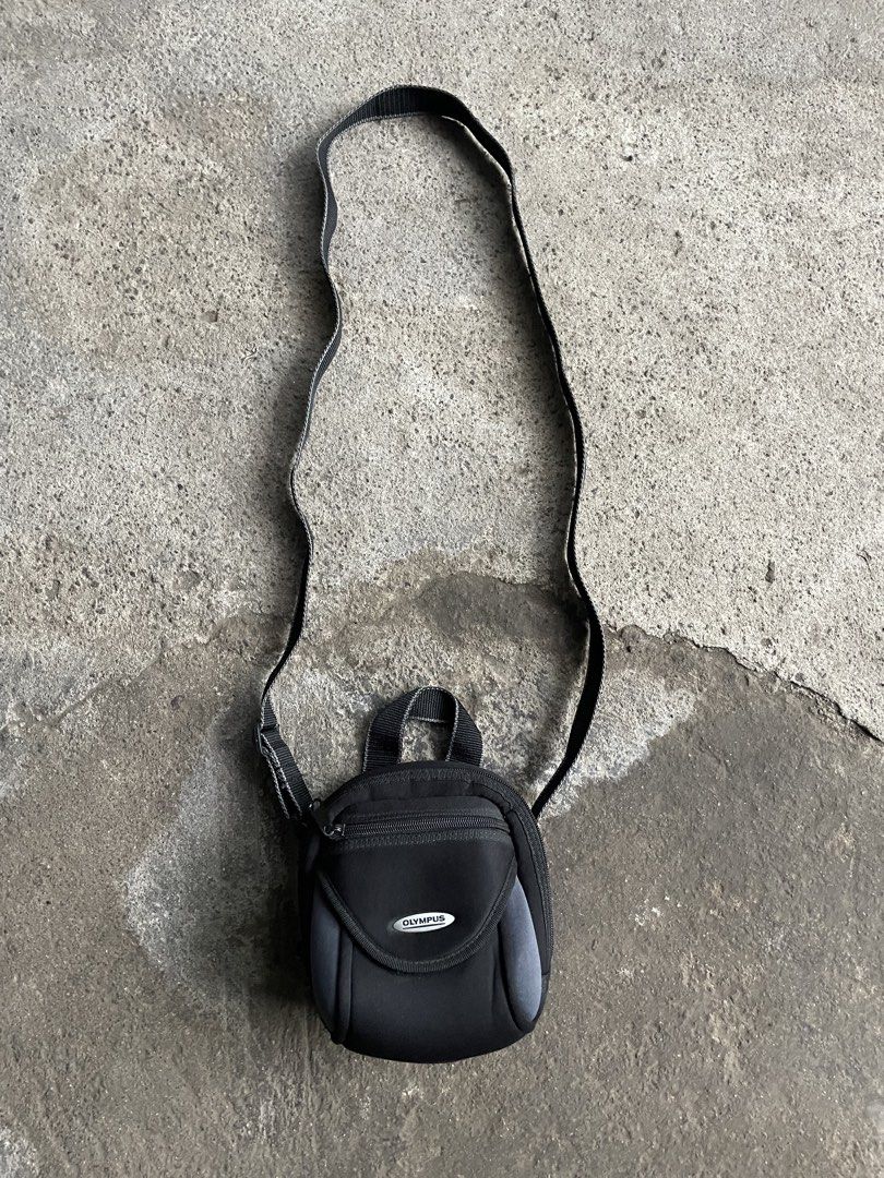 Olympus Black Camera Bag with Strap (Category: Camera Bags & Carriers) located in Polomolok. Submitted by madagascarts (Listing ID 1441304004, Image 1). Description: - Small black Olympus camera bag - Main zippered compartment - Smaller front pocket - Black fabric lined interior - Adjustable shoulder strap included - Ideal for protecting compact cameras on the go - Compact and lightweight design.