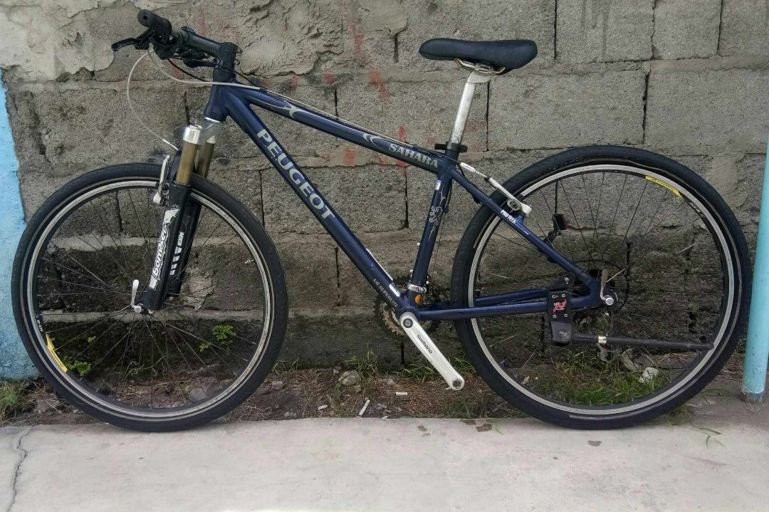 Peugeot Sahara Mountain Bike (Category: Bicycles) located in General Santos City (Dadiangas). Submitted by cclarimelvintageclassicretro (Listing ID 1441305560, Image 2). Description: - Peugeot Sahara mountain bike 26er (Alluminum) Size 14" ST / 21" TT 3x8speed - Dark blue frame with silver accents - Front suspension fork - Parallax hubs - Suitable for trails and city riding - Shows normal wear and tear consistent with use.