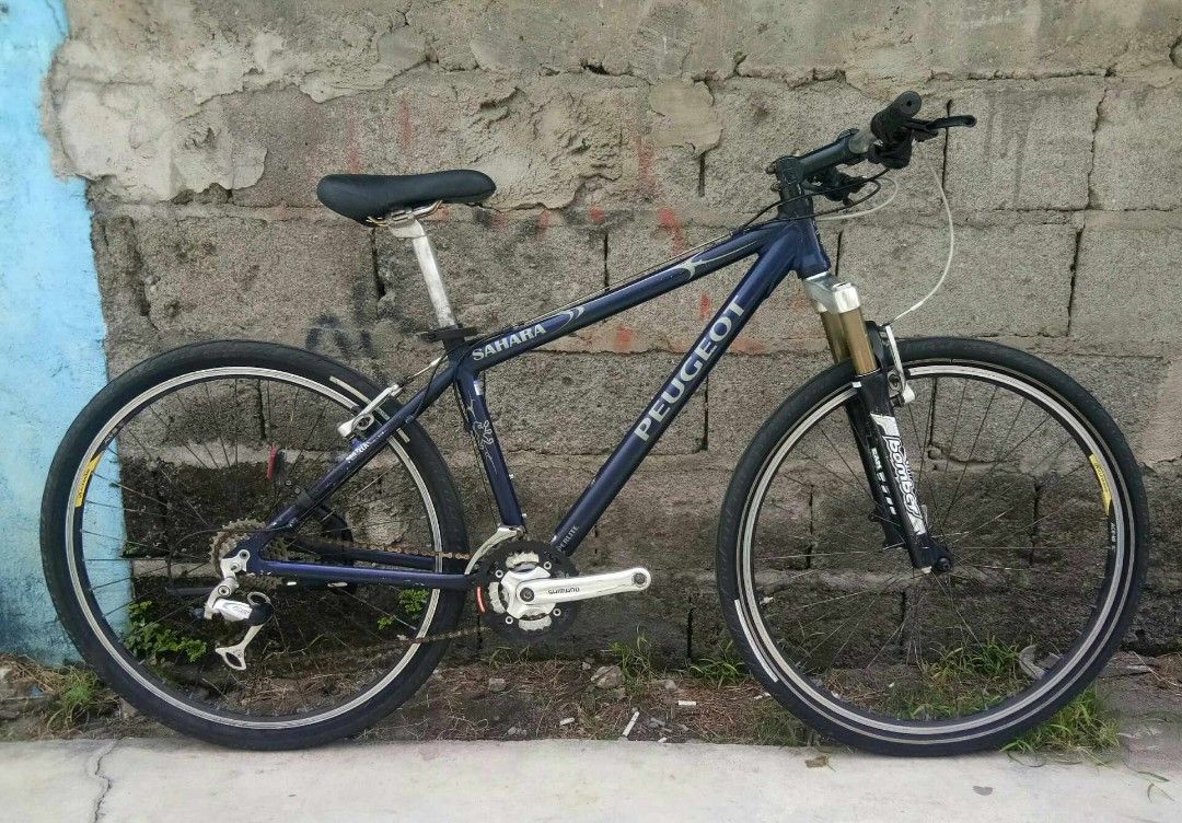 Peugeot Sahara Mountain Bike (Category: Bicycles) located in General Santos City (Dadiangas). Submitted by cclarimelvintageclassicretro (Listing ID 1441305560, Image 1). Description: - Peugeot Sahara mountain bike 26er (Alluminum) Size 14" ST / 21" TT 3x8speed - Dark blue frame with silver accents - Front suspension fork - Parallax hubs - Suitable for trails and city riding - Shows normal wear and tear consistent with use.
