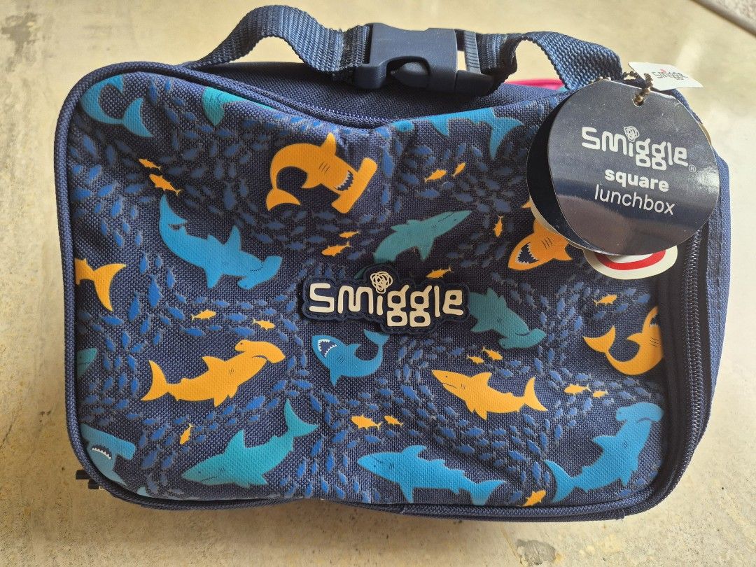 Brand new Smiggle Square Lunchboxes - Shark & Tropical Prints (Category: Babies & Kids Fashion) located in Singapore. Submitted by lucertola80299 (Listing ID 1441165148, Image 3). Description: - Set of 2 Smiggle square lunchboxes - Design 1: Navy blue with shark print - Design 2: Bright pink with tropical pattern - Both feature the Smiggle logo - Zippers are in good working condition - Ideal for school lunches or snacks.