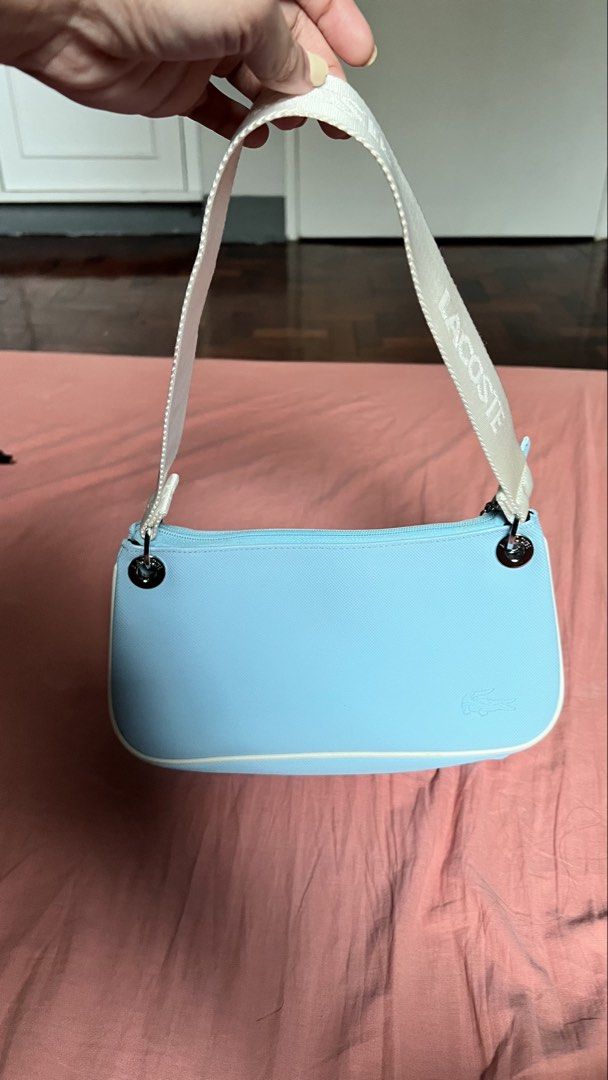 Vintage Lacoste Shoulder Bag Baguette (Category: Shoulder Bags) located in Cavite. Submitted by arleian (Listing ID 1441194971, Image 2). Description: - Adorable baby blue Lacoste shoulder bag. - Features the iconic embroidered crocodile logo on the front. - 'LACOSTE' branding printed on the strap. - Stylish white piping along the edges. - Secure zipper closure. - Ideal for everyday wear and casual outings. RFS: Declutterring. This is a gift from