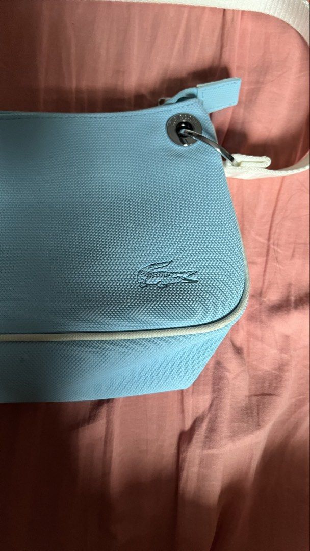 Vintage Lacoste Shoulder Bag Baguette (Category: Shoulder Bags) located in Cavite. Submitted by arleian (Listing ID 1441194971, Image 3). Description: - Adorable baby blue Lacoste shoulder bag. - Features the iconic embroidered crocodile logo on the front. - 'LACOSTE' branding printed on the strap. - Stylish white piping along the edges. - Secure zipper closure. - Ideal for everyday wear and casual outings. RFS: Declutterring. This is a gift from