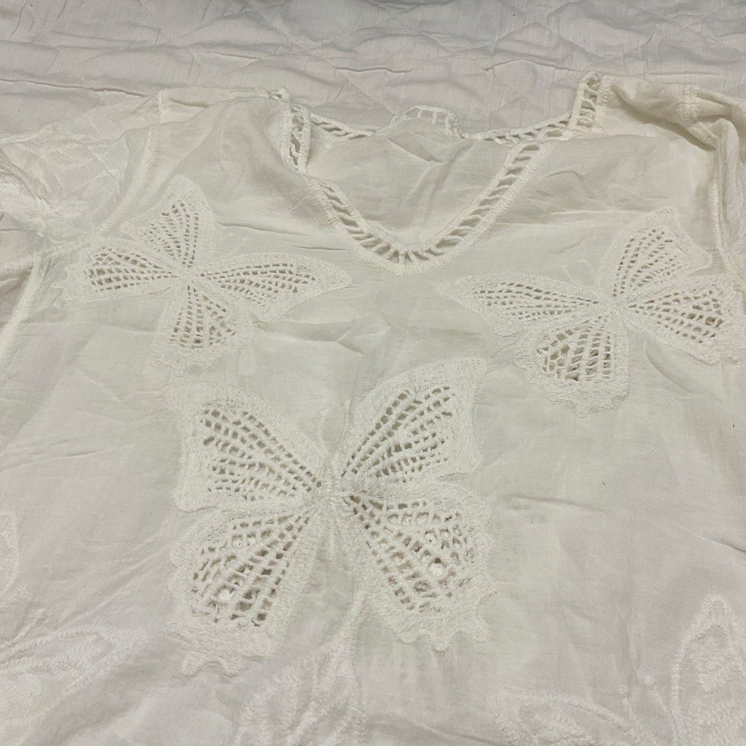 White Butterfly Embroidered V-Neck Top (Category: Sleeveless) located in Las Pinas. Submitted by jhoyiii (Listing ID 1441237748, Image 2). Description: - White short-sleeved top - Size: Medium - V-neck design - Intricate butterfly embroidery - Crochet-like hem detail - Lightweight and airy fabric - Ideal for casual outings or as a beach cover-up.