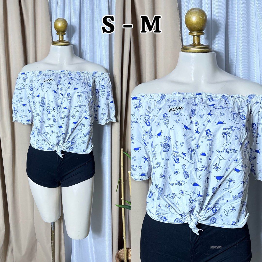 White Off-Shoulder Top with Blue Print - Size S-M (Category: Blouses) located in Meycauayan. Submitted by twinblessing (Listing ID 1441228140, Image 1). Description: - Cute off-shoulder design - Fun blue print - Front tie knot detail - Short sleeves with elastic - Versatile: pairs well with shorts or jeans - Perfect for casual outings or beach vibes - Easy to wear and style.