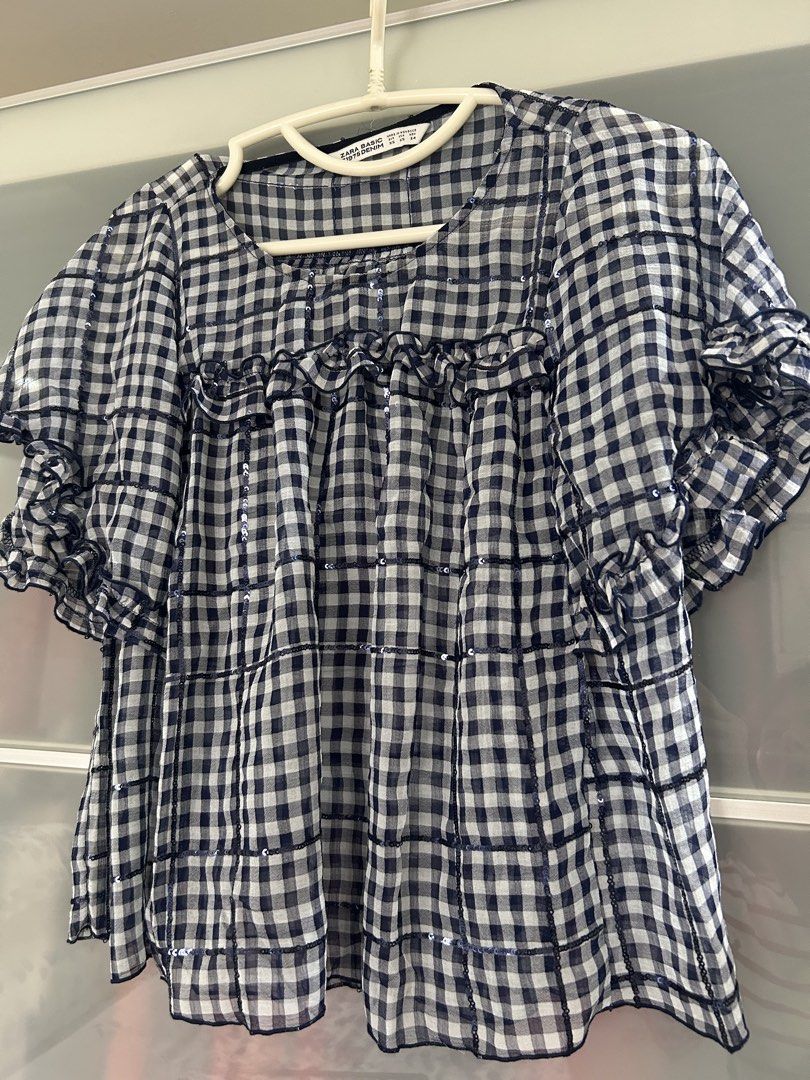 Zara Basic Gingham Sequin Top (Category: Blouses) located in Singapore. Submitted by traveltheworld12 (Listing ID 1441336774, Image 1). Description: - Cute navy and white gingham top from Zara Basic. - Features scattered sparkly sequins. - Ruffled and flowy sleeves. - Pretty ruffle detail on the neckline. - Perfect for dressing up or down..