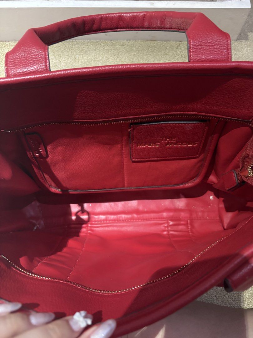 Marc Jacobs The Tote Bag Red Leather (Category: Luxury Bags & Wallets) located in Quezon. Submitted by squishymallows (Listing ID 1442967627, Image 3). Description: Selling a red Marc Jacobs tote bag. It's the classic 'The Tote Bag' model. Made from leather. Plenty of space inside for all your essentials. Has an inner zip pocket and a patch pocket. Great for everyday use or travel. - signs of use and unnoticeable leather crackings.