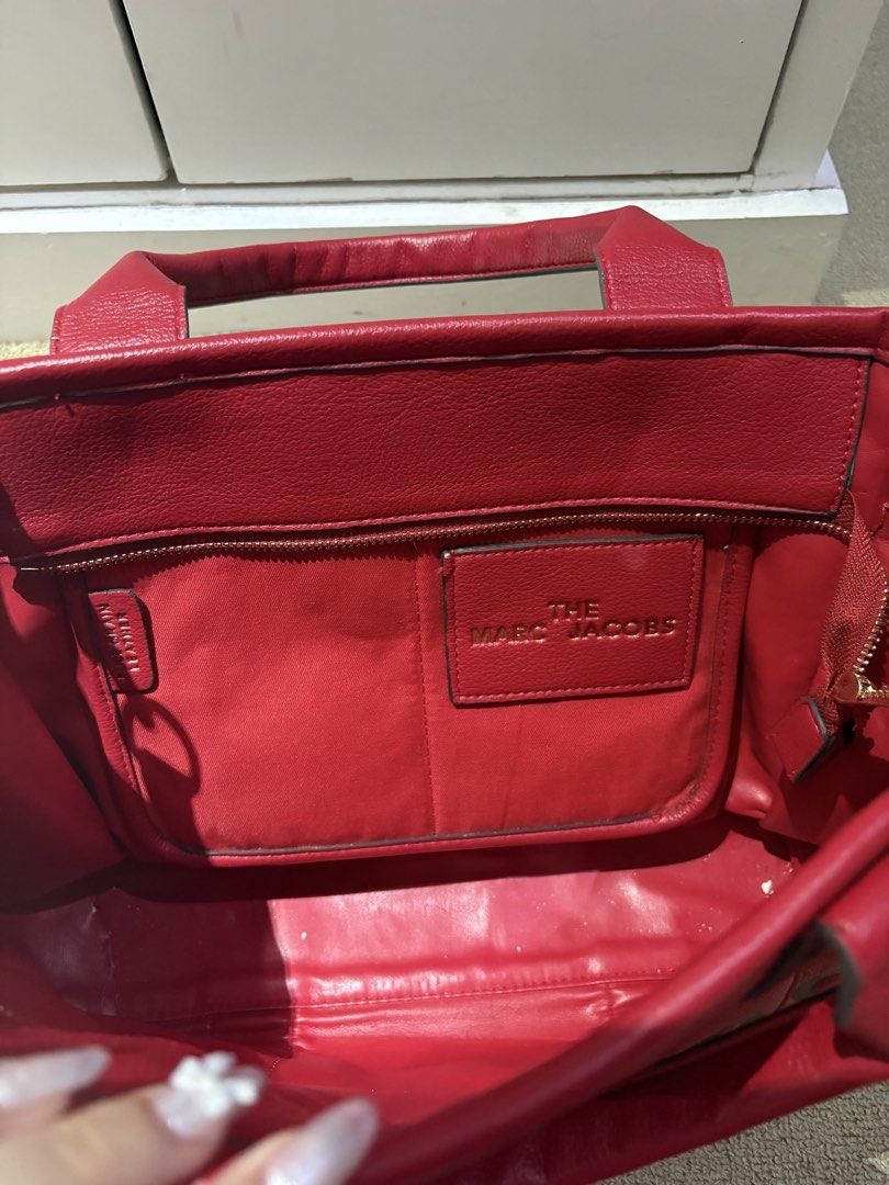 Marc Jacobs The Tote Bag Red Leather (Category: Luxury Bags & Wallets) located in Quezon. Submitted by squishymallows (Listing ID 1442967627, Image 2). Description: Selling a red Marc Jacobs tote bag. It's the classic 'The Tote Bag' model. Made from leather. Plenty of space inside for all your essentials. Has an inner zip pocket and a patch pocket. Great for everyday use or travel. - signs of use and unnoticeable leather crackings.