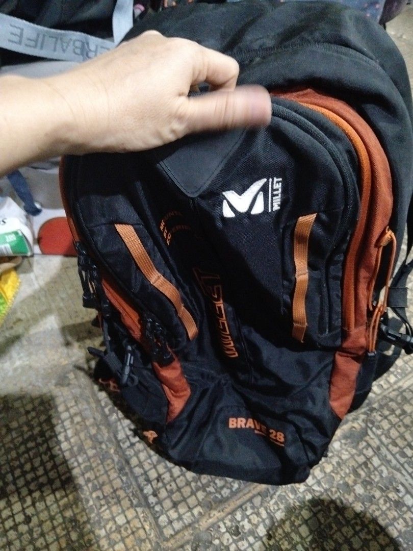 Millet Brave 28 Backpack - Black Orange (Category: Backpacks) located in El Salvador. Submitted by francheskaukayukay (Listing ID 1442934298, Image 1). Description: - Millet Brave 28 backpack - Color: Black with orange accents - "Stretch construction" printed on front - "Mountain by Experience" branding - Durable design suitable for outdoor activities - Features numerous straps and buckles for secure carrying - Ideal for hiking and travel.