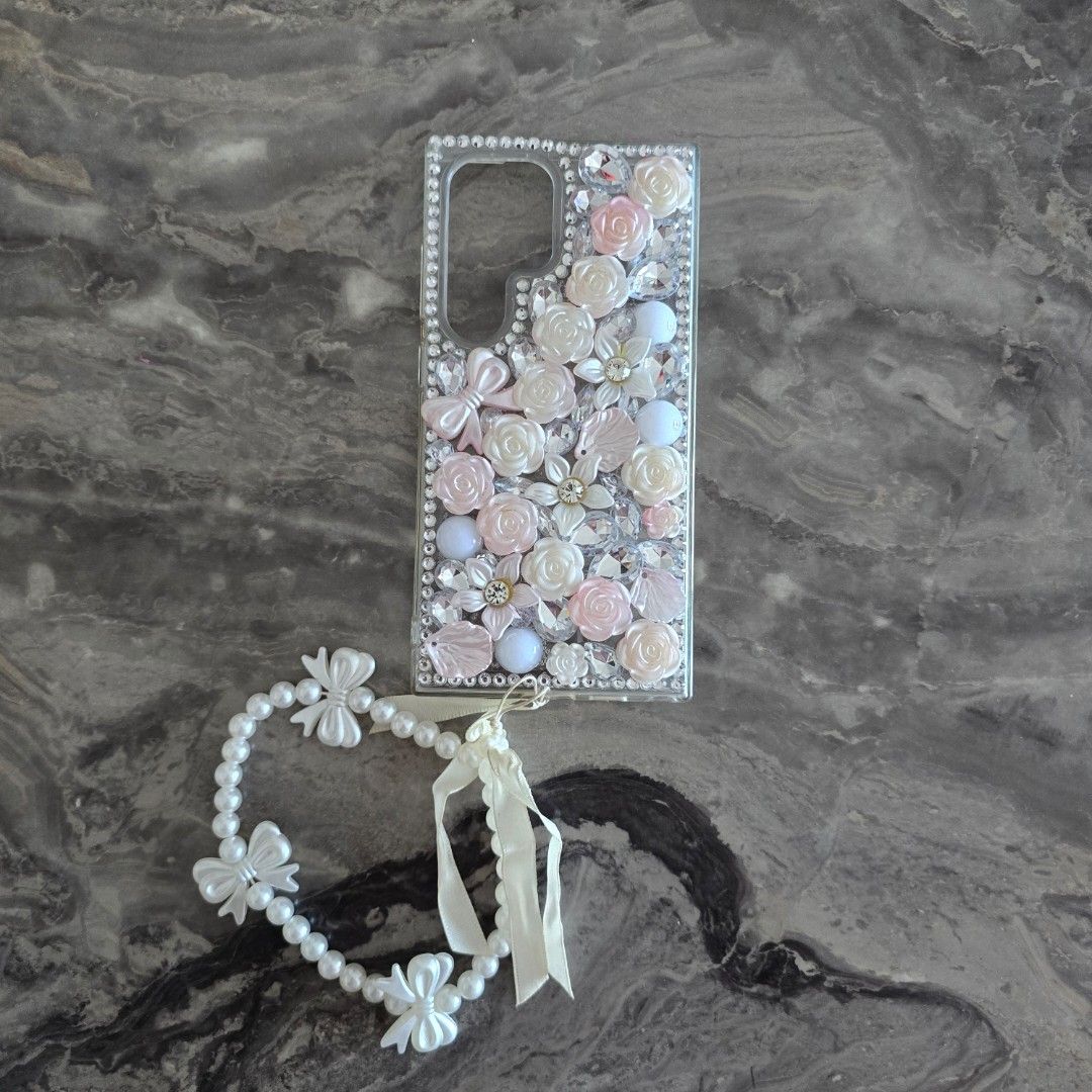 S24 Ultra Custom Bling Phone Case with Charm (Category: Cases & Sleeves) located in Mandaluyong City. Submitted by _monamourph (Listing ID 1442950164, Image 1). Description: - Super cute phone case adorned with dazzling rhinestones and charming 3D flowers. - Includes a matching pearl and bow charm strap for added flair. - Handmade and one-of-a-kind design. - Provides stylish protection for your phone. Bought for 450 in GH. Slightly used onlu sell