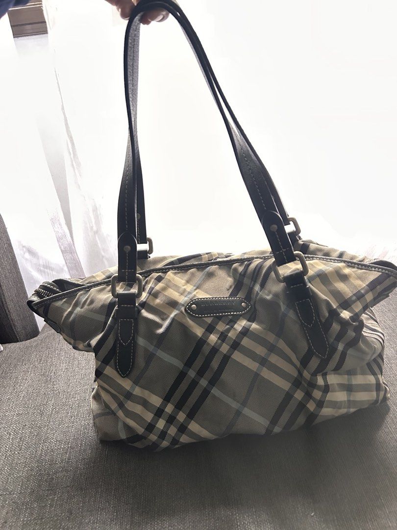 Burberry Bag (Category: Bags & Wallets) located in Singapore. Submitted by xoxo_elis (Listing ID 1443171663, Image 1). Description: - Authentic Burberry Blue Label tote - Iconic plaid pattern - Genuine leather trim and handles - Secure zipper closure - Convenient interior pocket - Spacious for everyday essentials - Rarely used; the back of bag is such due to storage - Comes as it is.
