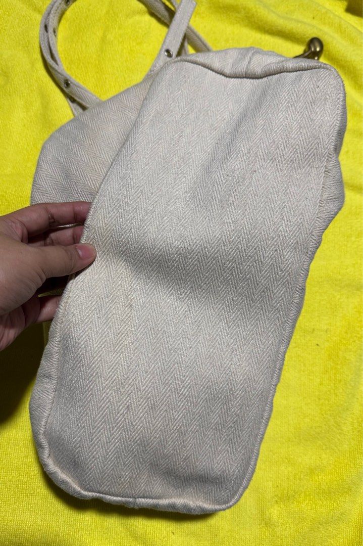 Cream Canvas Shoulder Bag with Zipper (Category: Shoulder Bags) located in Taytay. Submitted by jayezapanta (Listing ID 1443296058, Image 3). Description: - Cream colored canvas shoulder bag - Unique herringbone weave pattern - Secure zipper closure for main compartment - Adjustable strap with stylish metal eyelets - Minor faint marks on exterior fabric - Interior lining shows some staining and fraying near the top seam - A practical and versatil