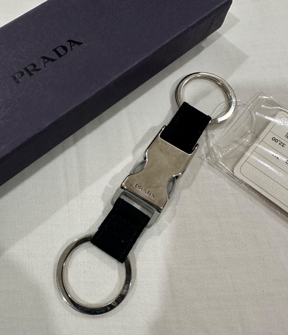 Prada Black Nylon Buckle Keychain with Box (Category: Luxury Accessories) located in San Juan City. Submitted by looneybin559 (Listing ID 1443271568, Image 3). Description: - Authentic Prada keychain - Black nylon strap with silver buckle closure - Comes with two key rings - Includes original Prada box - Stylish and simple accessory for keys or bags Never used. Just kept in storage. WYSIWYG. ***ITEM IS AVAILABLE IF YOU CAN SEE THIS MESSAGE. Pleas