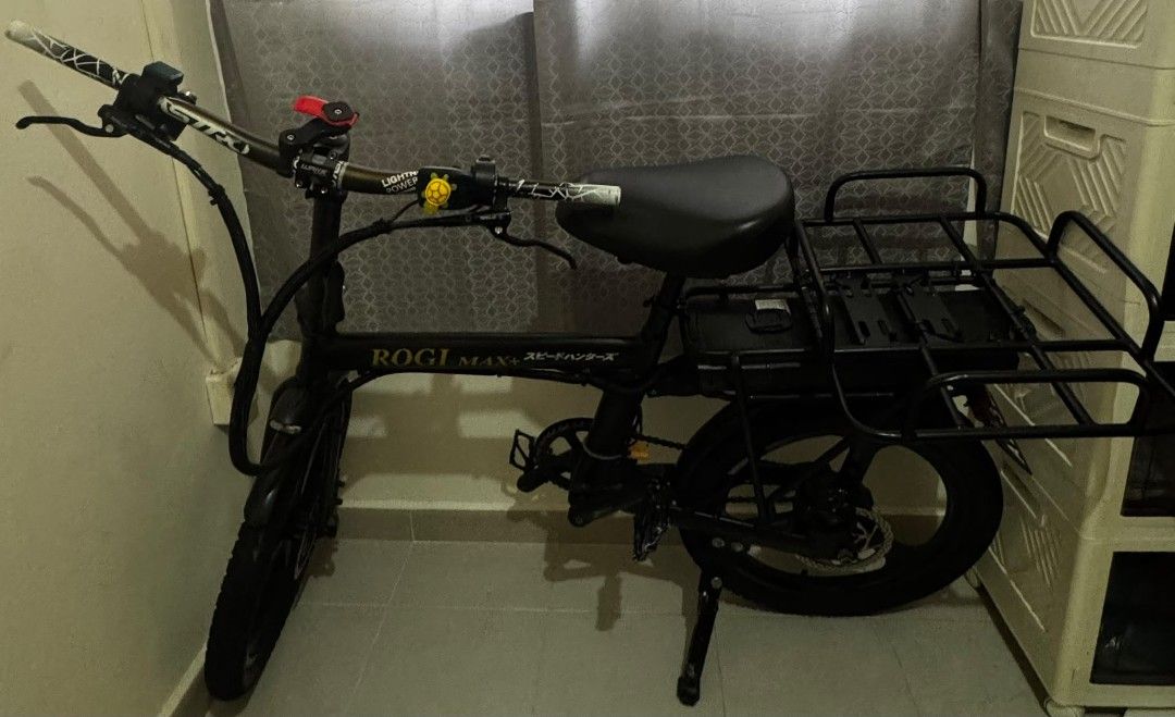 Rogi Max (Category: E-Scooters & E-Bikes) located in Singapore. Submitted by alexxeii (Listing ID 1443220146, Image 1). Description: Selling on behalf of a friend, price can be negotiated but not too low - Rogi Max+ folding e-bike in full black - 36V 21AH Battery + 2A Charger - Used for less than a month (like new) - Basic model: No LCD display (speed 25+, below 30 km/h) - Front and rear lights included, with horn - Upgraded Astro handlebars - Ad