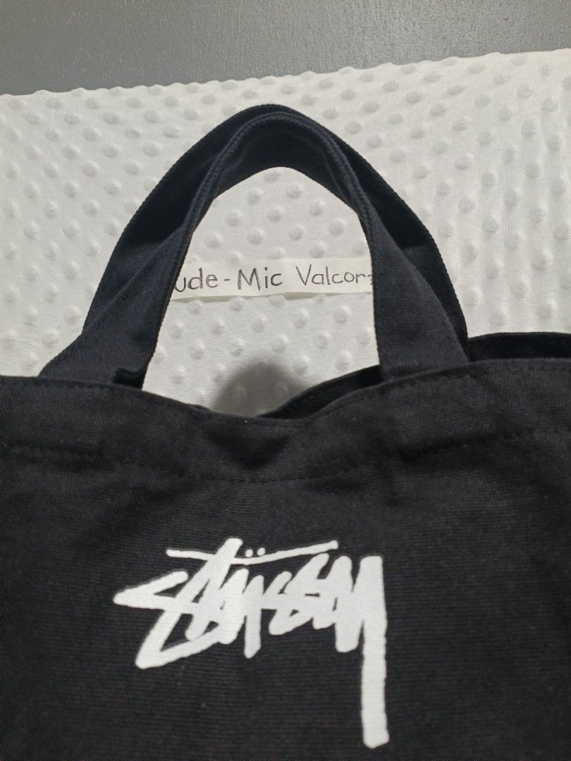 Stussy Black Canvas Tote Bag with Strap (Category: Tote Bags) located in Tanay. Submitted by micvalcorza (Listing ID 1443274995, Image 2). Description: - Brand: Stussy - Color: Black - Material: Canvas - Features: Top handles, detachable shoulder strap, printed Stussy logo on front, interior pockets - Closure: Snap button - Size: Good for everyday use.
