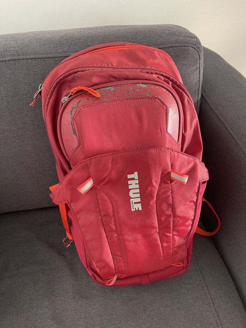 Thule Red Backpack (Category: Backpacks) located in Taguig. Submitted by supplementary (Listing ID 1443221818, Image 1). Description: - Red Thule backpack - Orange accents on straps and zippers - Padded shoulder straps for comfort - Ideal for everyday use or travel - Note: Some scuffs on the front pocket area.