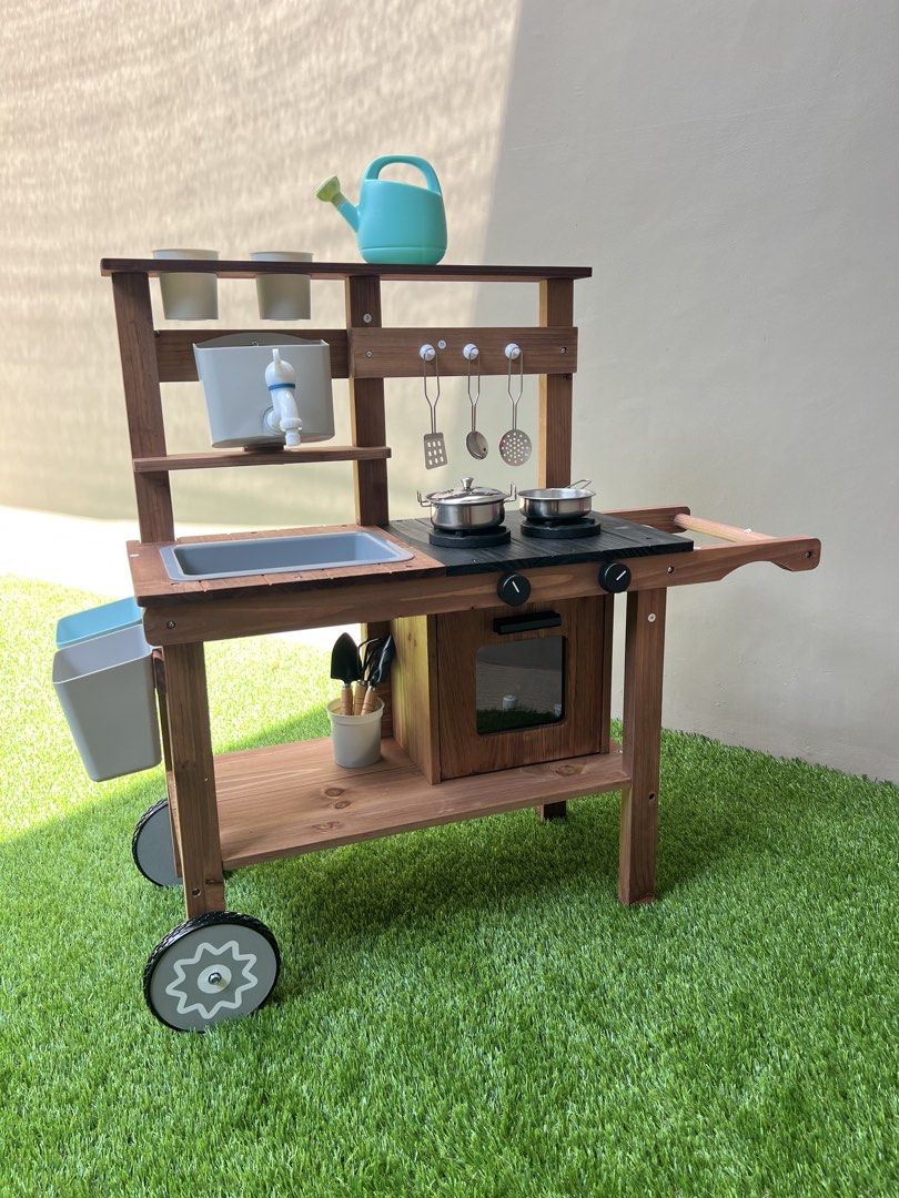 Wooden Mud Kitchen Playset with Accessories (Category: Kids Toys) located in Mandaluyong City. Submitted by timberthinksph (Listing ID 1443271658, Image 2). Description: - Sturdy wooden mud kitchen for kids - Includes sink, stovetop, and oven - Comes with hanging utensils, pots, watering can, and gardening tools - Ideal for outdoor imaginative play - Features wheels for easy portability.