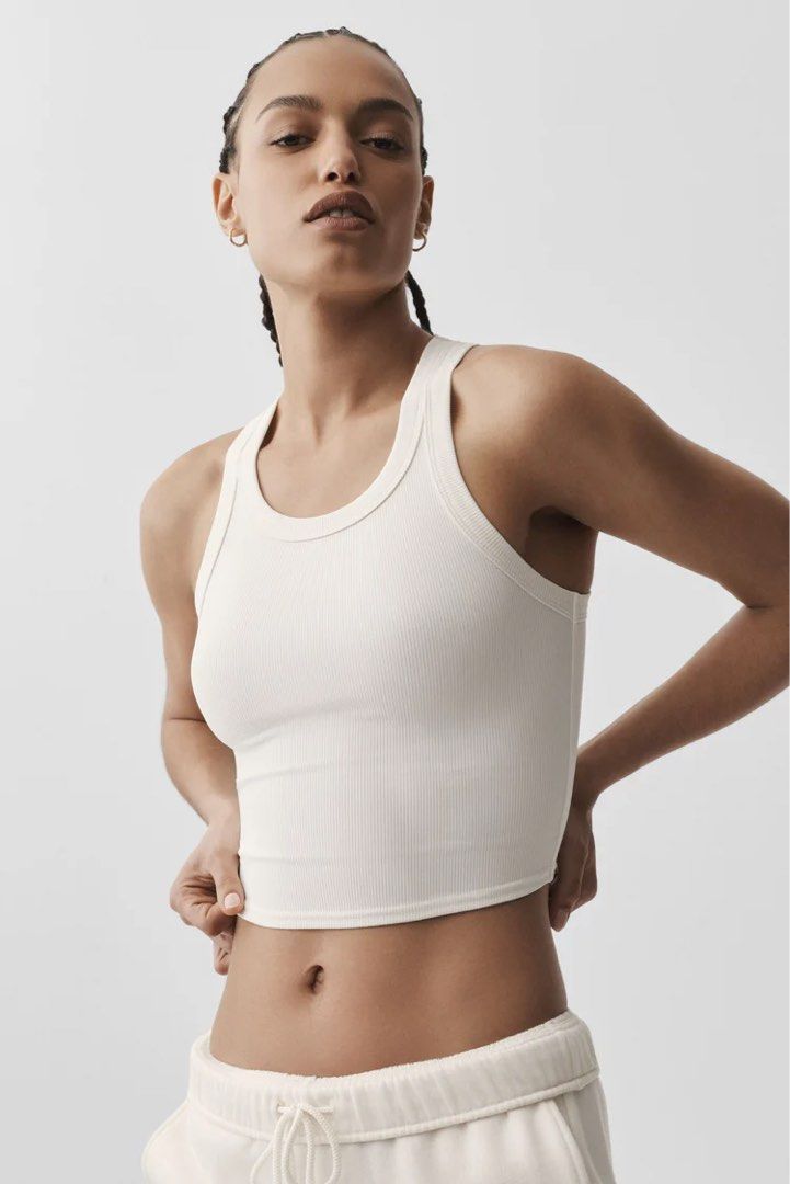 Alo Goddess Ribbed Go-To Tank White XS (Category: Activewear) located in Singapore. Submitted by shopthemoon (Listing ID 1443344295, Image 1). Description: - RTP: $94 - Brand: Alo - Style: Ribbed cropped tank top - Features: Racerback, performance fabric, light compression - Fit: Stretchy and super comfy - Versatile: Perfect for workouts or casual wear.