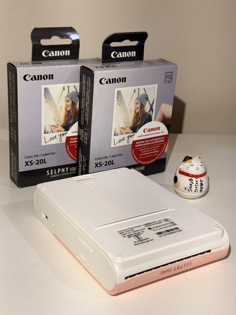 Canon Selphy Square QX10 + FREE 2 BOXES Ink Sets (Category: Printers, Scanners & Copiers) located in Quezon City. Submitted by waterwait (Listing ID 1443462163, Image 2). Description: Canon Selphy Square QX10 in pink 💗 Pre-loved, very good condition. Fully working and well-maintained. Ideal for journaling & scrapbooking. Purchased at Henry’s Cameras (online). Unit only with charging cable. FREE two (2) boxes of Canon XS-20L Color Ink/Label Sets: