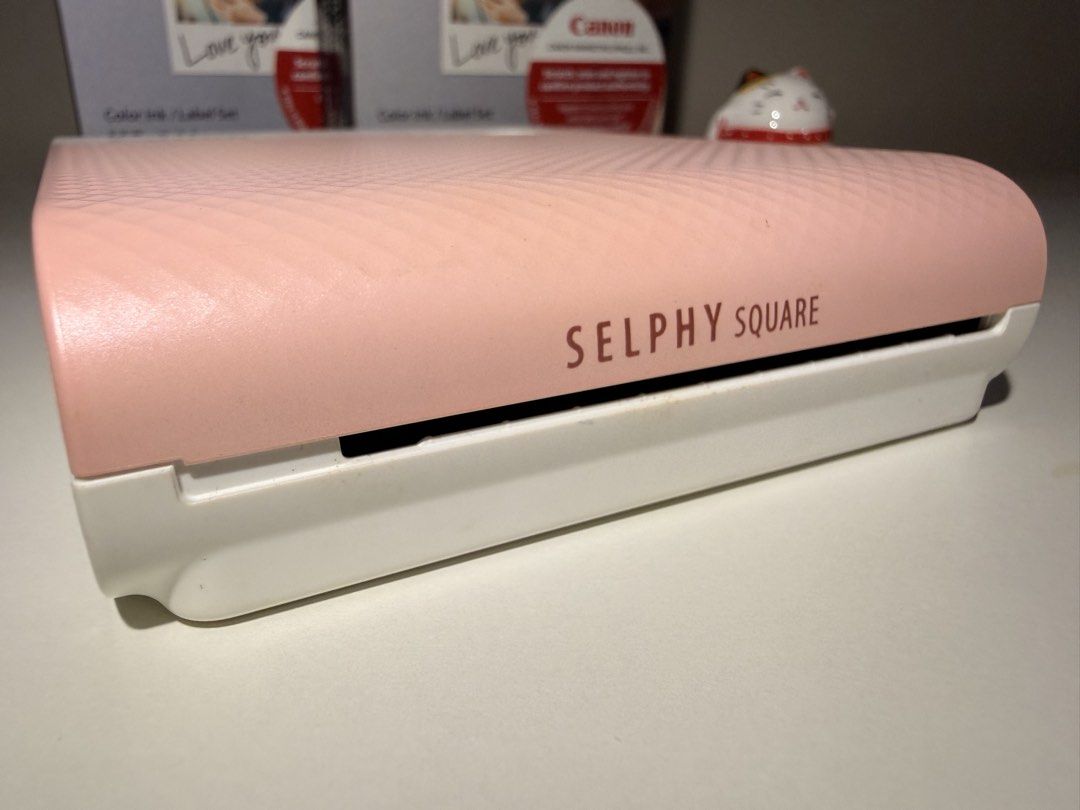 Canon Selphy Square QX10 + FREE 2 BOXES Ink Sets (Category: Printers, Scanners & Copiers) located in Quezon City. Submitted by waterwait (Listing ID 1443462163, Image 3). Description: Canon Selphy Square QX10 in pink 💗 Pre-loved, very good condition. Fully working and well-maintained. Ideal for journaling & scrapbooking. Purchased at Henry’s Cameras (online). Unit only with charging cable. FREE two (2) boxes of Canon XS-20L Color Ink/Label Sets: