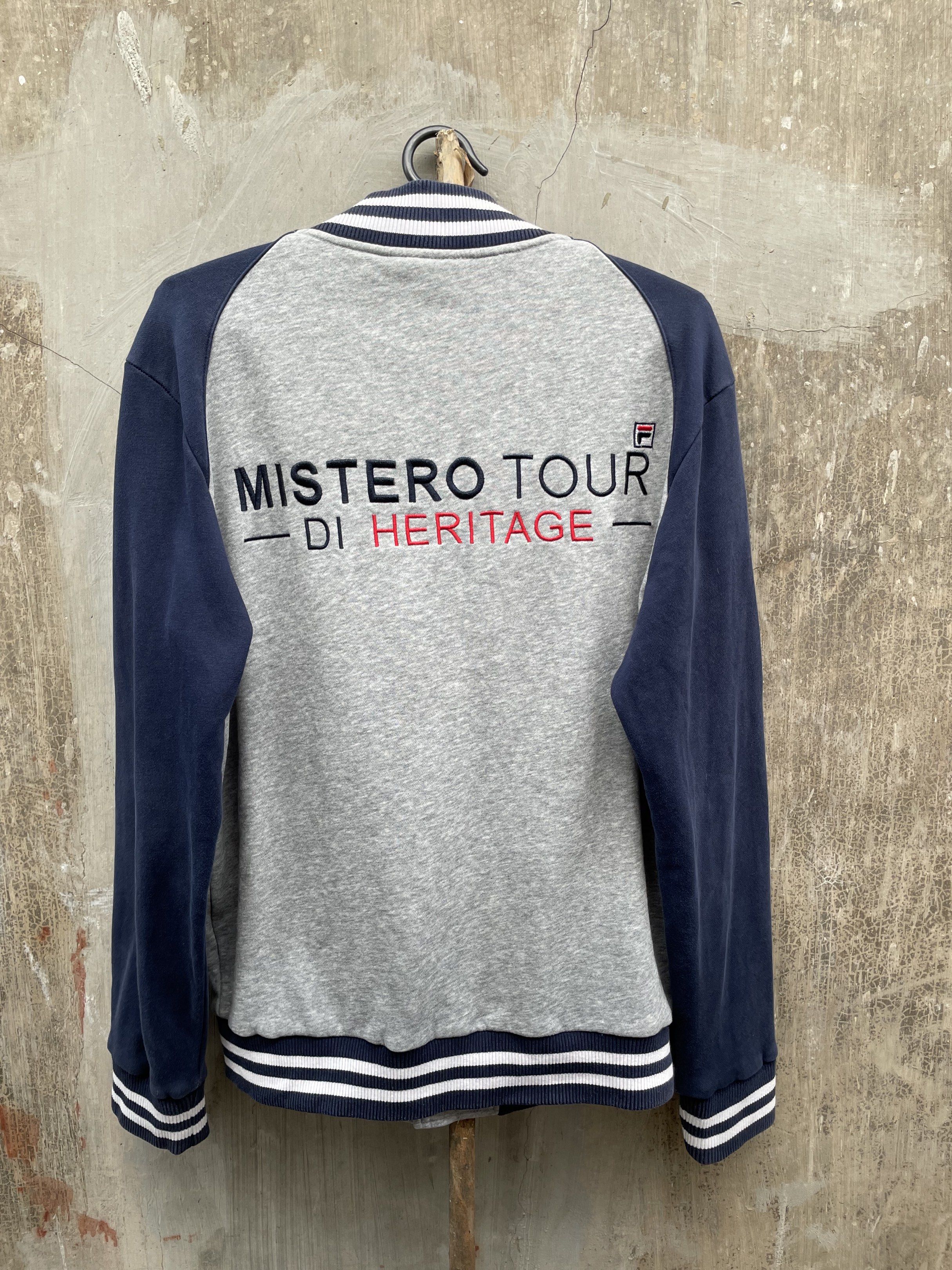 Fila Italia Heritage Varsity Jacket Grey Navy L (Category: Coats, Jackets and Outerwear) located in Calasiao. Submitted by jeekloots (Listing ID 1443324821, Image 2). Description: - Grey and navy Fila varsity jacket - Size: L - Fila logo on the front - 'Mistero Tour di Heritage' embroidery on the back - Ribbed cuffs, collar, and hem - Button-up front - Pockets.
