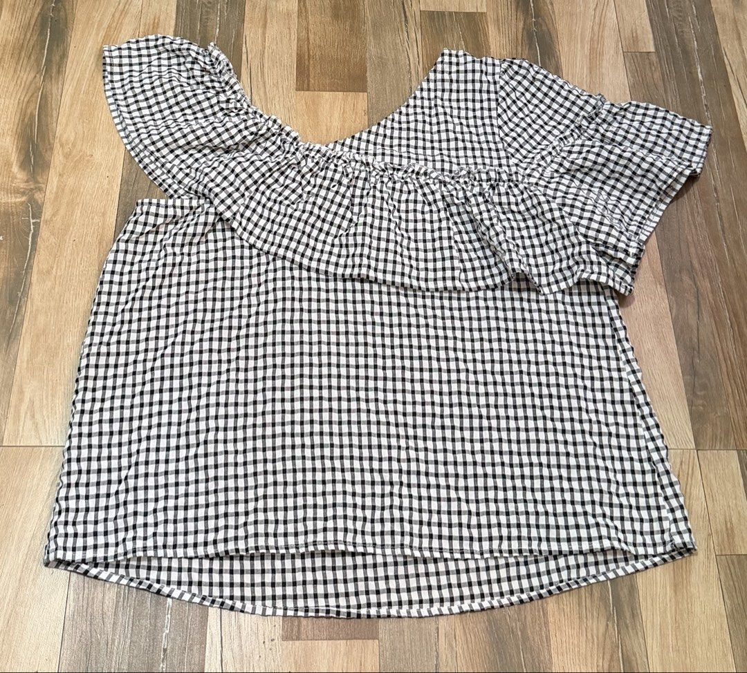 Gingham Ruffle One Shoulder Top (Category: Sleeveless) located in Taytay. Submitted by shopbye (Listing ID 1443421266, Image 1). Description: - Trendy black and white gingham pattern - Chic one-shoulder design - Adorable ruffled detail across the chest - Flared sleeves for a stylish touch - Versatile: dress it up or down for any occasion.