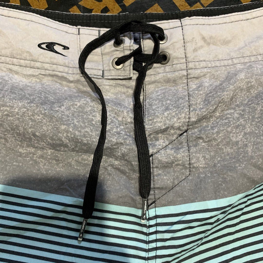 O'Neill Board Shorts Size 32 (Category: Swim Trunks & Board Shorts) located in Cebu City. Submitted by stuff_paid (Listing ID 1443332601, Image 3). Description: - Brand: O'Neill - Size: 32 - Material: 100% Polyester - Features: Black cargo pocket on the side, drawstring waist - Design: Striped pattern with grey, black, and light blue - Ideal for: Swimming, surfing.