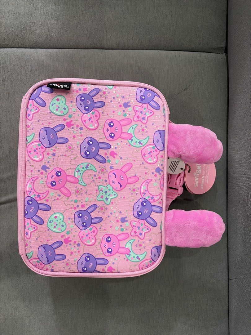 ORIGINAL Smiggle Pink Bunny Ears Lunch Box Bag (Category: Babies & Kids Fashion) located in Quezon City. Submitted by rosellesantos (Listing ID 1443434015, Image 2). Description: - Adorable pink Smiggle lunch bag - Features a cute bunny face on the front - Fun all-over bunny and star print on the back - Adorned with fluffy bunny ears - Secure zipper closure - Ideal for school lunches or day trips.