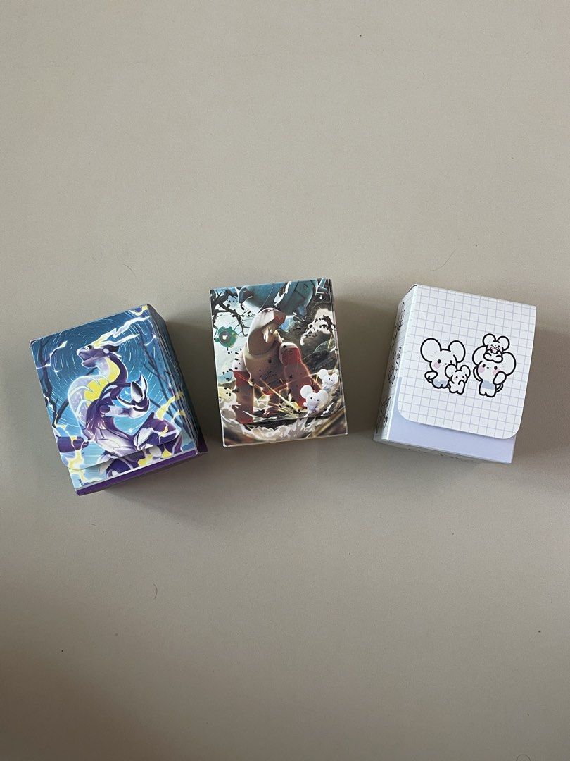 Pokemon Card Game Deck Boxes - Choose 1 for 500 (Category: Card Boxes & Cases) located in Manila. Submitted by shopandscore (Listing ID 1443346659, Image 1). Description: - Official Pokemon Card Game deck boxes - Three unique designs available: - Cool dragon design - Large creature with smaller mice - Cute mouse characters on a grid background - Keep your Pokemon cards organized and protected - Ideal for collectors and players in the Philippines.