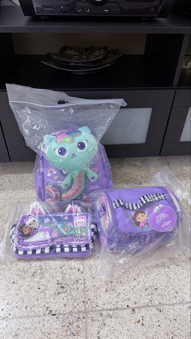 Smiggle Gabby's Dollhouse Backpack, Pencil Case & Lunchbox Set (Category: Babies & Kids Fashion) located in Quezon City. Submitted by somethingshady (Listing ID 1443401950, Image 1). Description: - Brand new Smiggle Gabby's Dollhouse set - Includes: Backpack with mermaid cat plush, pencil case, and cylindrical lunchbox - Color: Purple with character graphics - Perfect for fans of Gabby's Dollhouse - All items are still in their original packaging