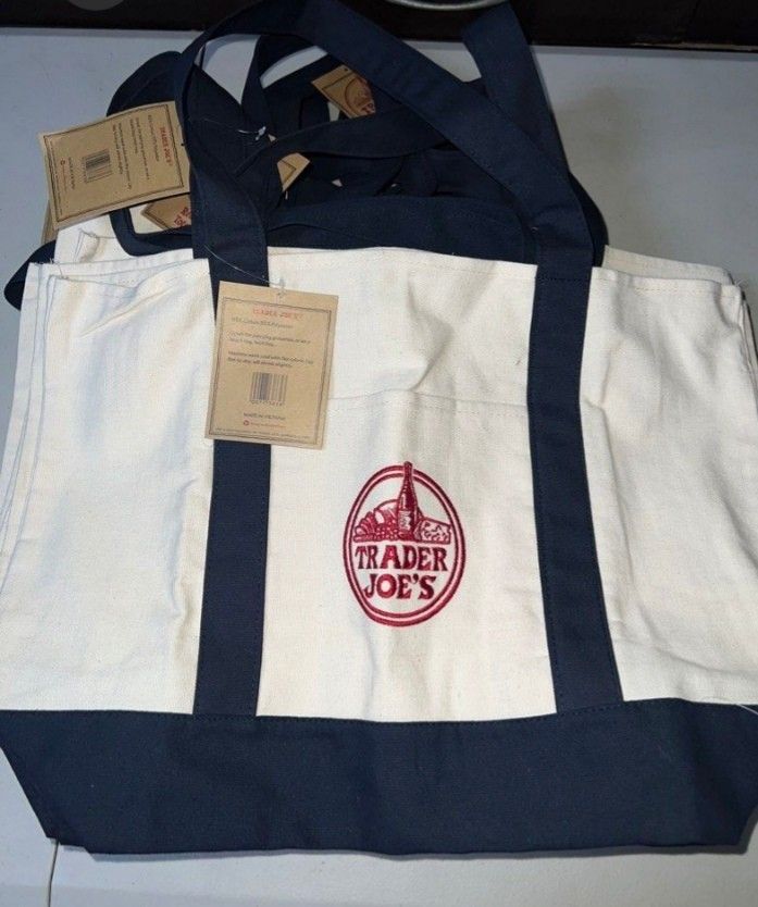 Trader Joe's Canvas Tote Bag (BIG) (Category: Tote Bags) located in Taguig. Submitted by juls0607 (Listing ID 1443426156, Image 3). Description: - Trader Joe's Big size Tote Bag - Features sturdy handles - White canvas body with dark blue/navy blue accents on bottom and handles - Features embroidered Trader Joe's logo on the side by side pocket made of canvas material - Ideal for grocery shopping or everyday errands - Durable and reusable - 100% 