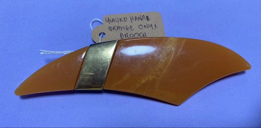 Yukiko Hanai Orange Onyx Brooch (Category: Brooches) located in Mabalacat. Submitted by somethingoldsomethingnew28 (Listing ID 1443429170, Image 1). Description: - Vintage Yukiko Hanai brooch - Features a striking orange onyx stone - Gold-tone metal accent - Approximately 4 inches long - Secure pin closure - Ideal statement piece for jackets, scarves, or bags.