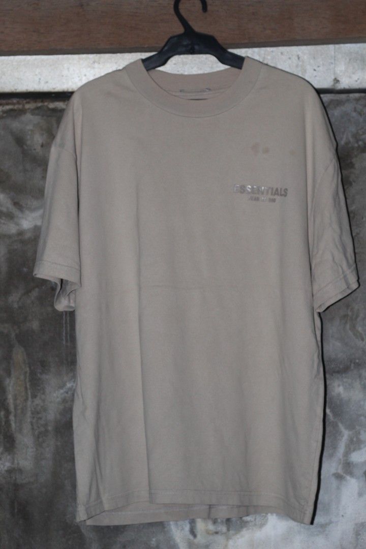Fear of God Essentials T-shirt (Category: Tshirts & Polo Shirts ) located in Manila. Submitted by poisonthrift (Listing ID 1443656409, Image 1). Description: - Brand: Fear of God Essentials - Color: Tan - Style: Short sleeve, crew neck t-shirt - Features: Small logo detail on chest - Condition: Good, with a few faint marks on the front - Ideal for: Casual wear.