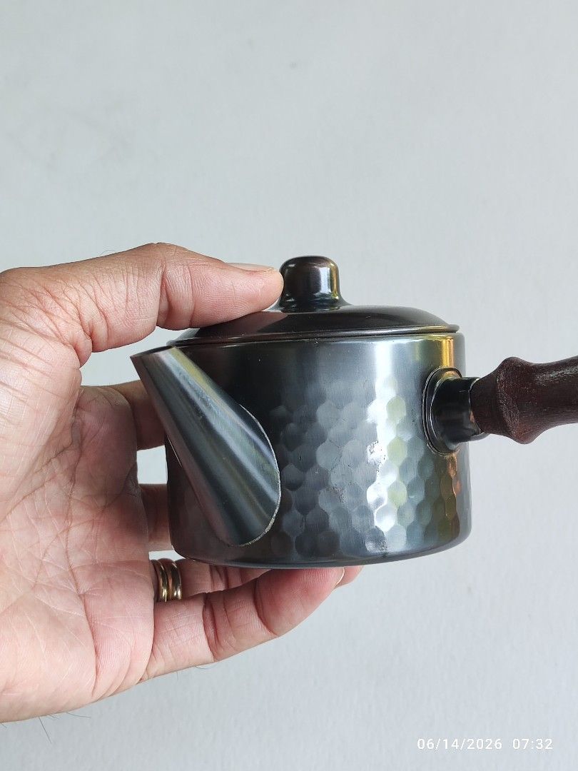Hammered Copper Teapot with Wooden Handle (Category: Coffee & Tea Tableware) located in Tagum. Submitted by cs1907 (Listing ID 1443701207, Image 1). Description: - Small teapot with a unique hammered metal exterior. - Features a comfortable dark wooden handle. - Snugly fitting lid ensures a good pour. - Versatile: perfect for serving tea or as a charming decorative piece. - Great addition to a small kitchen or any tea lover's collection..