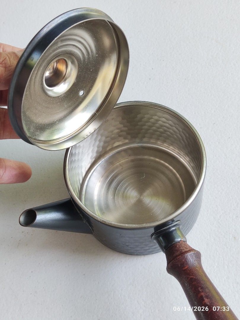 Hammered Copper Teapot with Wooden Handle (Category: Coffee & Tea Tableware) located in Tagum. Submitted by cs1907 (Listing ID 1443701207, Image 2). Description: - Small teapot with a unique hammered metal exterior. - Features a comfortable dark wooden handle. - Snugly fitting lid ensures a good pour. - Versatile: perfect for serving tea or as a charming decorative piece. - Great addition to a small kitchen or any tea lover's collection..