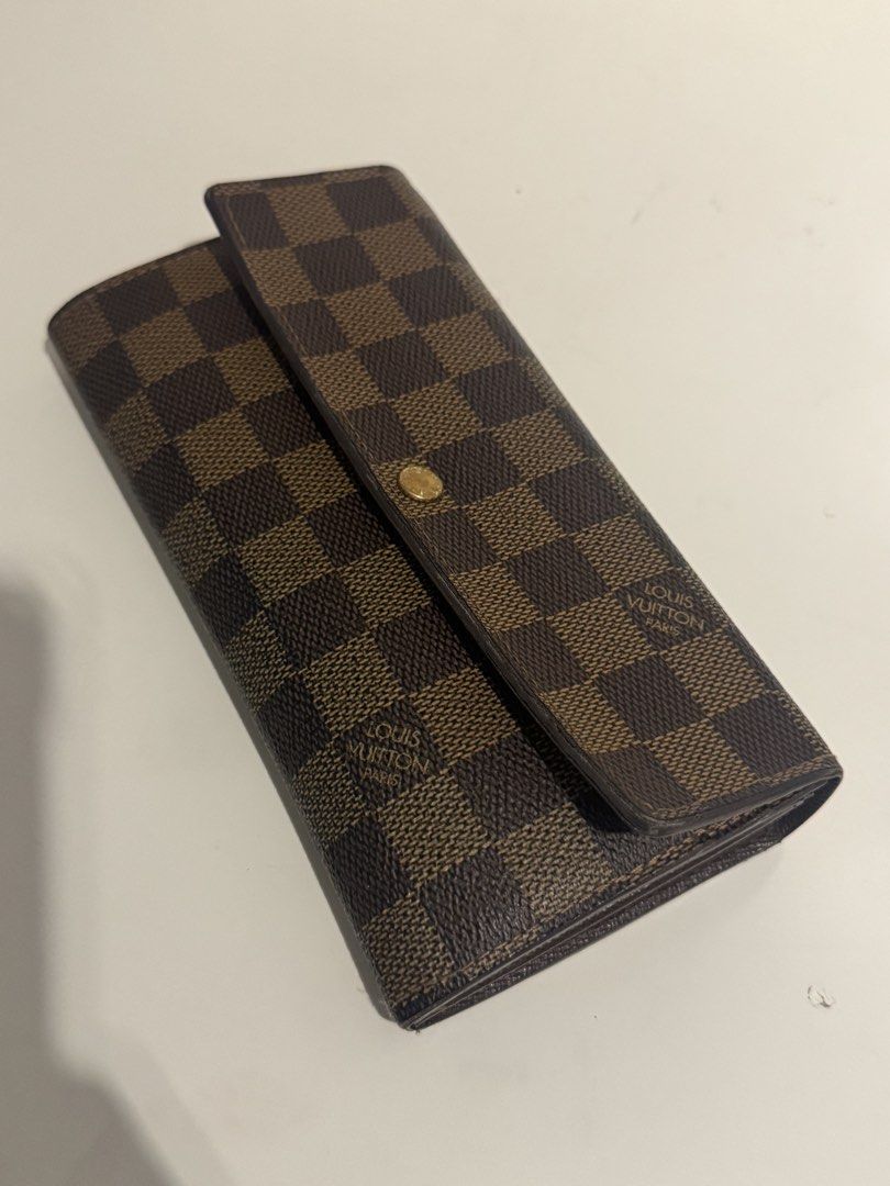 Louis Vuitton Damier Ebene Sarah Wallet (Category: Luxury Bags & Wallets) located in Pasig City. Submitted by acffashion31 (Listing ID 1443692591, Image 2). Description: - Authentic Louis Vuitton Sarah Wallet - Damier Ebene Canvas - Classic checkered pattern - Multiple card slots and compartments - Secure snap button closure - Ideal for everyday use - Flaws: Rubs inner part as seen in the last photo - Money back guaranteed.