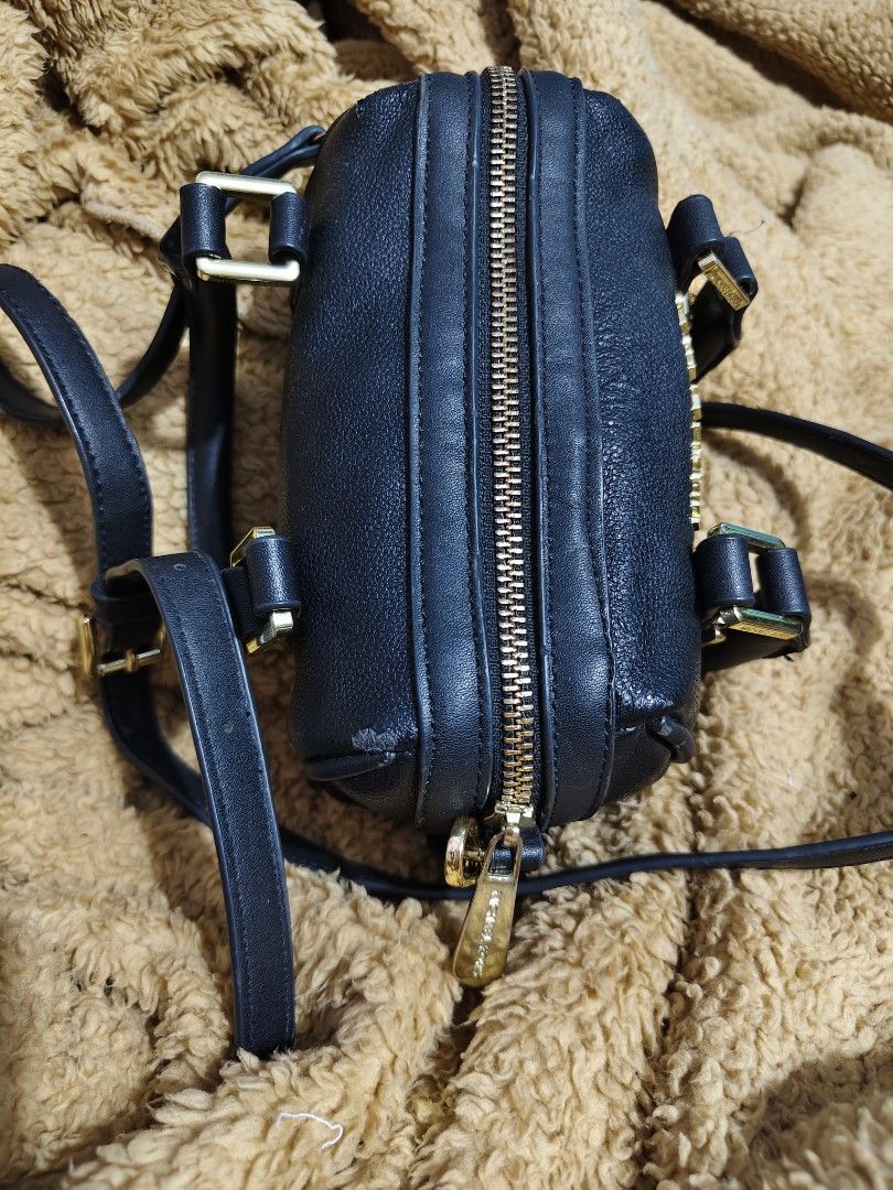 Michael Kors Black Leather Mini Duffle Bag (Category: Luxury Bags & Wallets) located in Makati City. Submitted by tin_erwin (Listing ID 1443599456, Image 3). Description: - Michael Kors mini duffle bag in black. - Crafted from textured leather with elegant gold hardware (some have oxidized). - Features comfortable top handles. - Includes a detachable crossbody strap for versatile wear. - Secure zipper closure. - Interior slip pocket for small ess