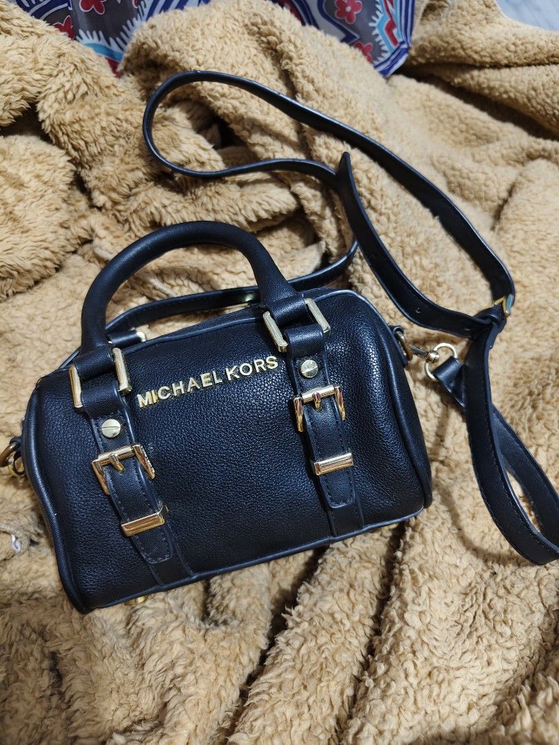 Michael Kors Black Leather Mini Duffle Bag (Category: Luxury Bags & Wallets) located in Makati City. Submitted by tin_erwin (Listing ID 1443599456, Image 1). Description: - Michael Kors mini duffle bag in black. - Crafted from textured leather with elegant gold hardware (some have oxidized). - Features comfortable top handles. - Includes a detachable crossbody strap for versatile wear. - Secure zipper closure. - Interior slip pocket for small ess