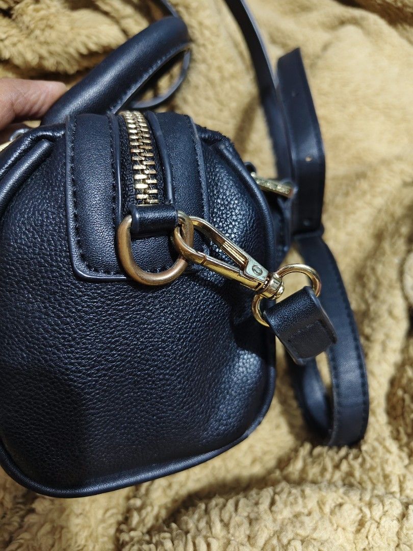 Michael Kors Black Leather Mini Duffle Bag (Category: Luxury Bags & Wallets) located in Makati City. Submitted by tin_erwin (Listing ID 1443599456, Image 2). Description: - Michael Kors mini duffle bag in black. - Crafted from textured leather with elegant gold hardware (some have oxidized). - Features comfortable top handles. - Includes a detachable crossbody strap for versatile wear. - Secure zipper closure. - Interior slip pocket for small ess