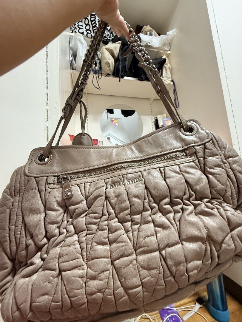 Miu Miu Ruched Leather Shoulder Bag (Category: Luxury Bags & Wallets) located in Pasig City. Submitted by rachereal11 (Listing ID 1443546483, Image 2). Description: - Taupe Miu Miu shoulder bag - Soft, ruched leather exterior - Silver turn-lock closure - Chain and leather strap - Purple satin interior lining - Interior zip pocket - Minor signs of wear on hardware and leather - Ideal for everyday use -Please self authenticate as I have no means to