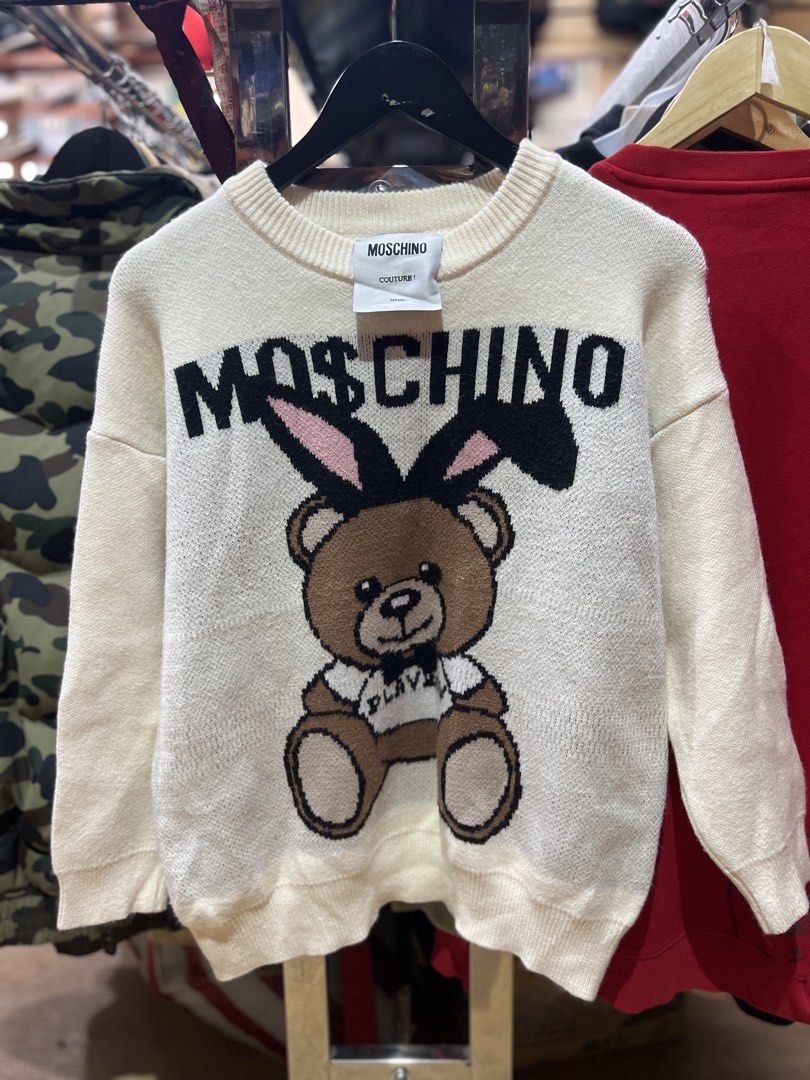 Moschino Teddy Bear Bunny Ears Knit Sweater (Category: Coats, Jackets and Outerwear) located in Baguio. Submitted by Muramura (Listing ID 1443555835, Image 1). Description: - Brand: Moschino - Color: Cream - Style: Knit Sweater - Design: Iconic teddy bear graphic with bunny ears - Logo: Moschino logo across the chest and on the back - Features: Cozy and fun - Occasion: Great for casual wear.