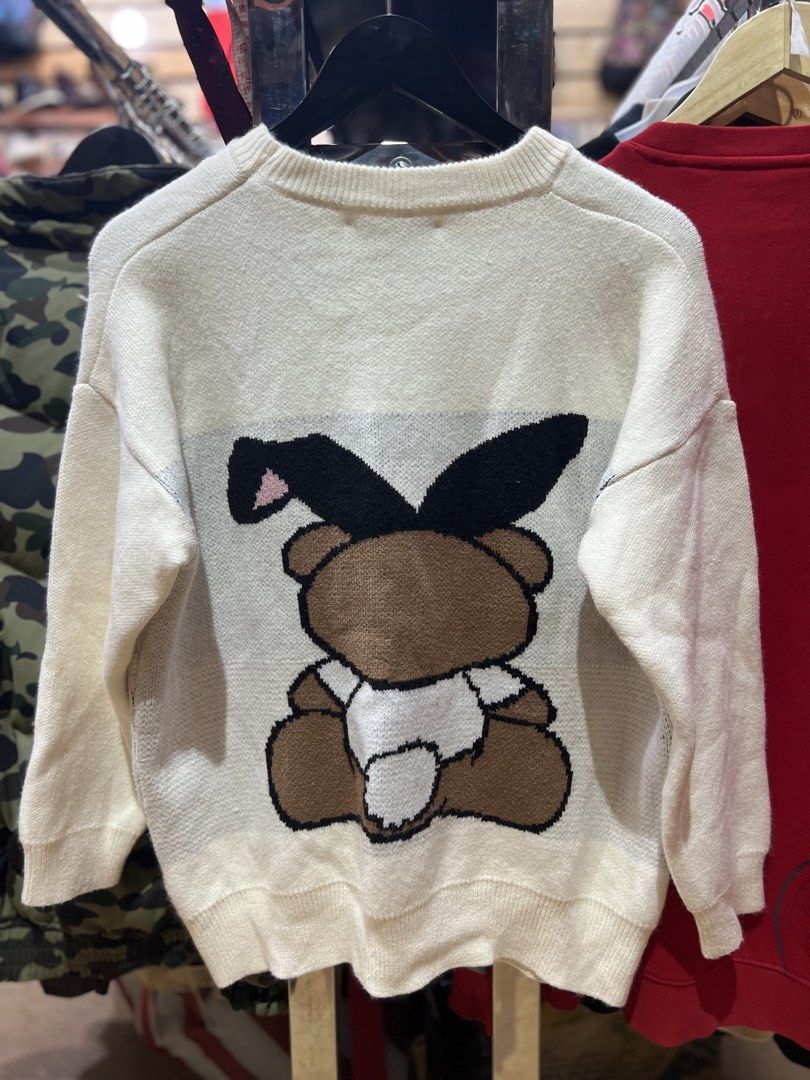 Moschino Teddy Bear Bunny Ears Knit Sweater (Category: Coats, Jackets and Outerwear) located in Baguio. Submitted by Muramura (Listing ID 1443555835, Image 3). Description: - Brand: Moschino - Color: Cream - Style: Knit Sweater - Design: Iconic teddy bear graphic with bunny ears - Logo: Moschino logo across the chest and on the back - Features: Cozy and fun - Occasion: Great for casual wear.