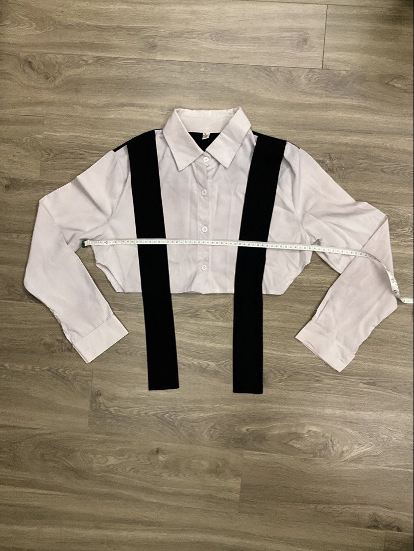 White Cropped Shirt with Black Tie (Category: Shirts) located in Las Pinas. Submitted by getl22 (Listing ID 1443512604, Image 2). Description: - White long-sleeved cropped shirt - Features black straps across the front - Button-up closure - Unique and versatile design - Great for layering or wearing solo.