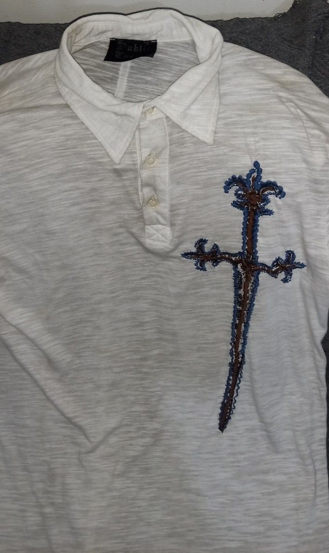 White Polo Shirt with Sword Embroidery (Category: Tshirts & Polo Shirts ) located in Cagayan de Oro. Submitted by edwardryan01984 (Listing ID 1443661314, Image 2). Description: - White short-sleeved polo shirt - Features a unique sword embroidery on the chest - Textured fabric for a premium feel - Classic button-up neckline - Ideal for casual outings and everyday style.