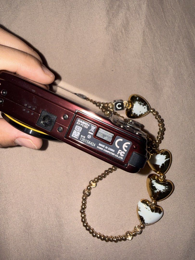 Casio EXILIM Digital Camera with Charm Strap (Category: Cameras) located in Las Pinas. Submitted by coolthreadz (Listing ID 1443880874, Image 2). Description: - Cute maroon Casio EXILIM digital camera - 5x optical zoom - Comes with a beaded charm strap with heart details - Features stickers on the front - Screen has minor scratches - Perfect for capturing memories.