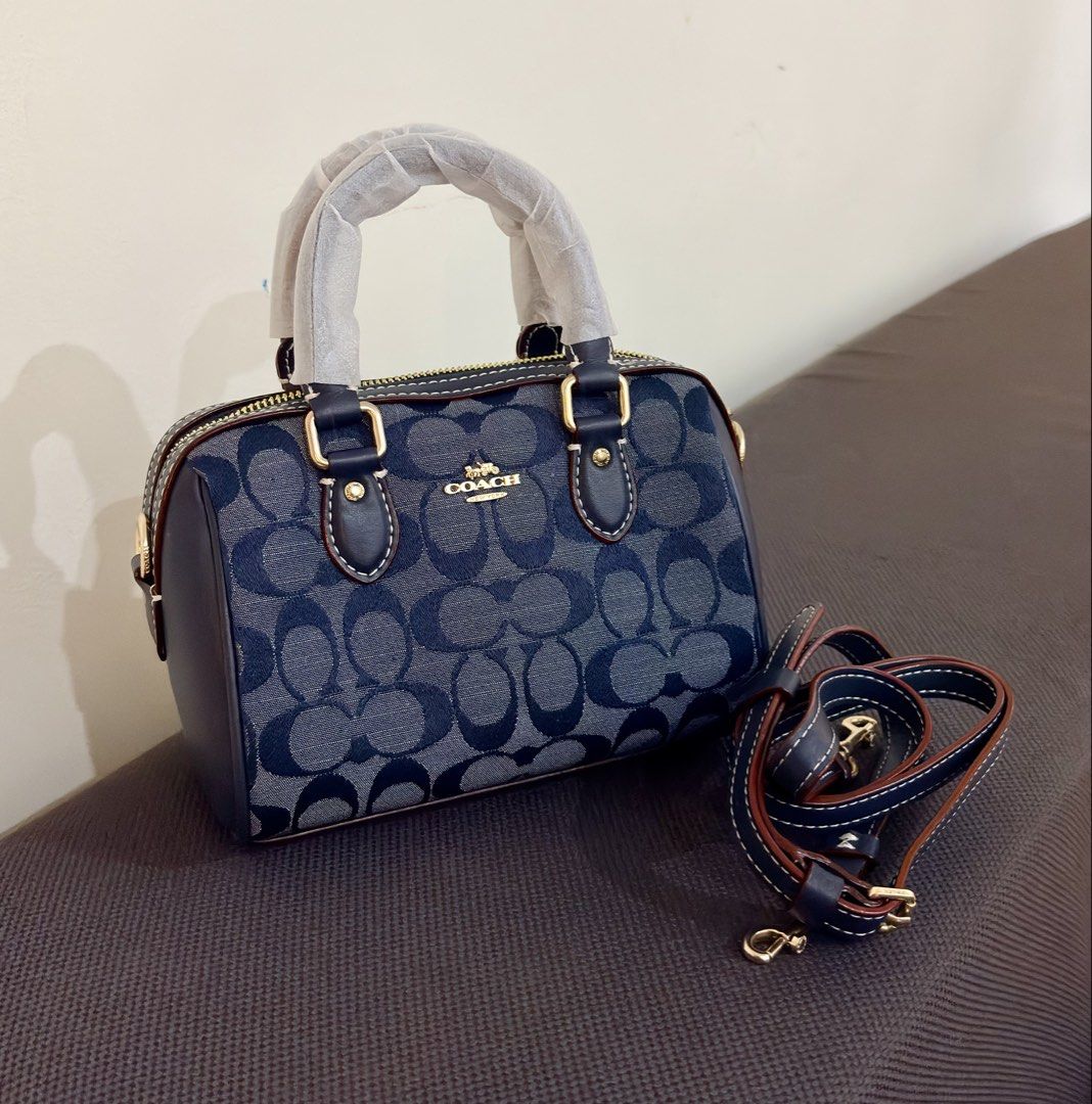 Coach Denim Mini Rowan (Category: Luxury Bags & Wallets) located in Manila. Submitted by klonlines03584 (Listing ID 1443869868, Image 1). Description: - Coach Mini Speedy bag - Classic denim signature print - Elegant gold hardware details - Includes a detachable shoulder strap for versatile wear - Handles still have protective plastic wrap - Ideal for everyday errands or a stylish night out.